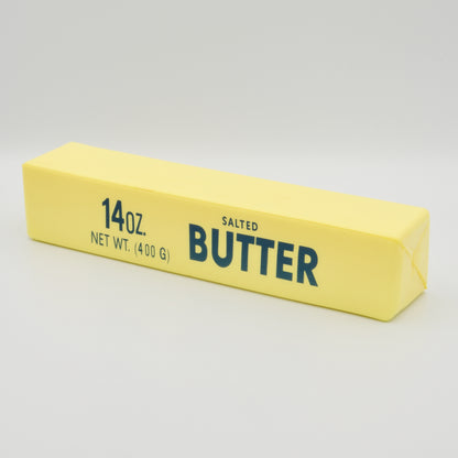 Gelber Antistress-Knetriegel in Butter-Optik mit Aufdruck „Salted Butter“, schräge Seitenansicht