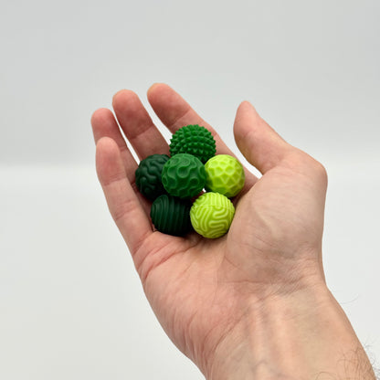 Grüne Fidgnetics Magnetkugeln mit verschiedenen Oberflächen in der Hand – Fidget Toy für Hände