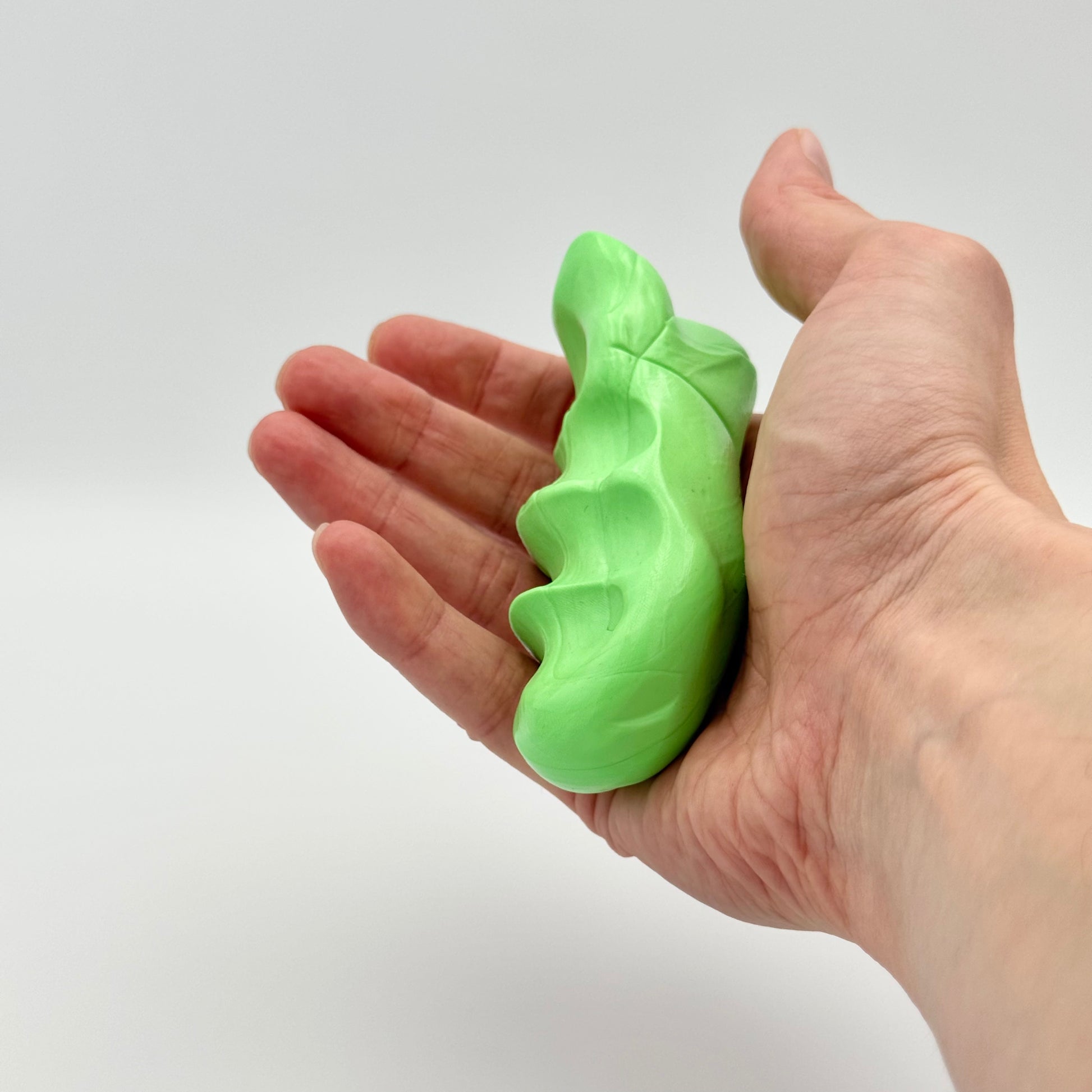 Hand drückt grüne Therapieknete – Fitness Knete für Finger- und Handtraining bei Stress