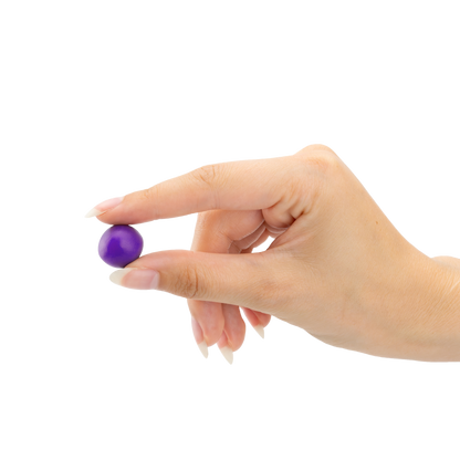 Eine Hand hält einen lila, verformbaren Gehörschutz-Stöpsel zwischen den Fingern vor schwarzem Hintergrund.