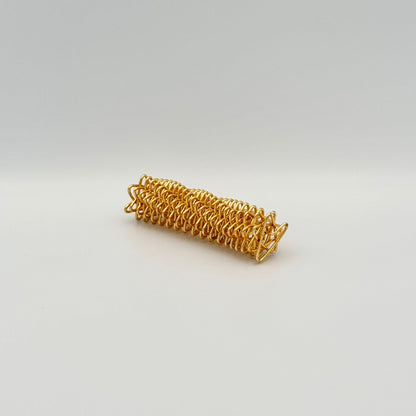 Goldene Handmassagerolle aus Metallfeder liegend – Akupressur Skill Tool für die Hände