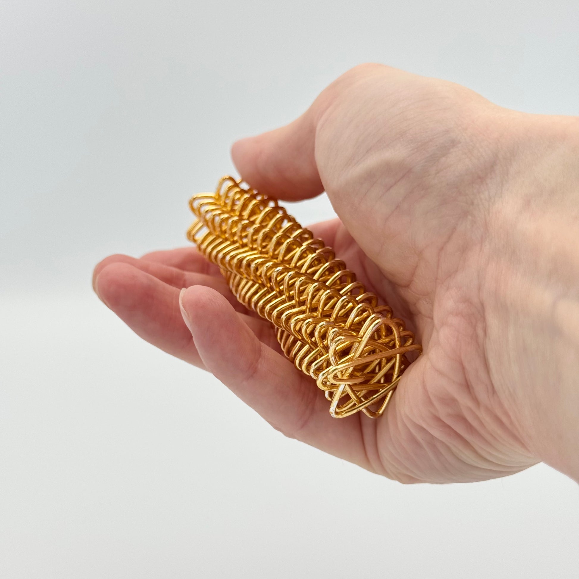 Goldene Handmassagerolle in der Hand – Feder-Massagerolle zur Akupressur & Fokussierung
