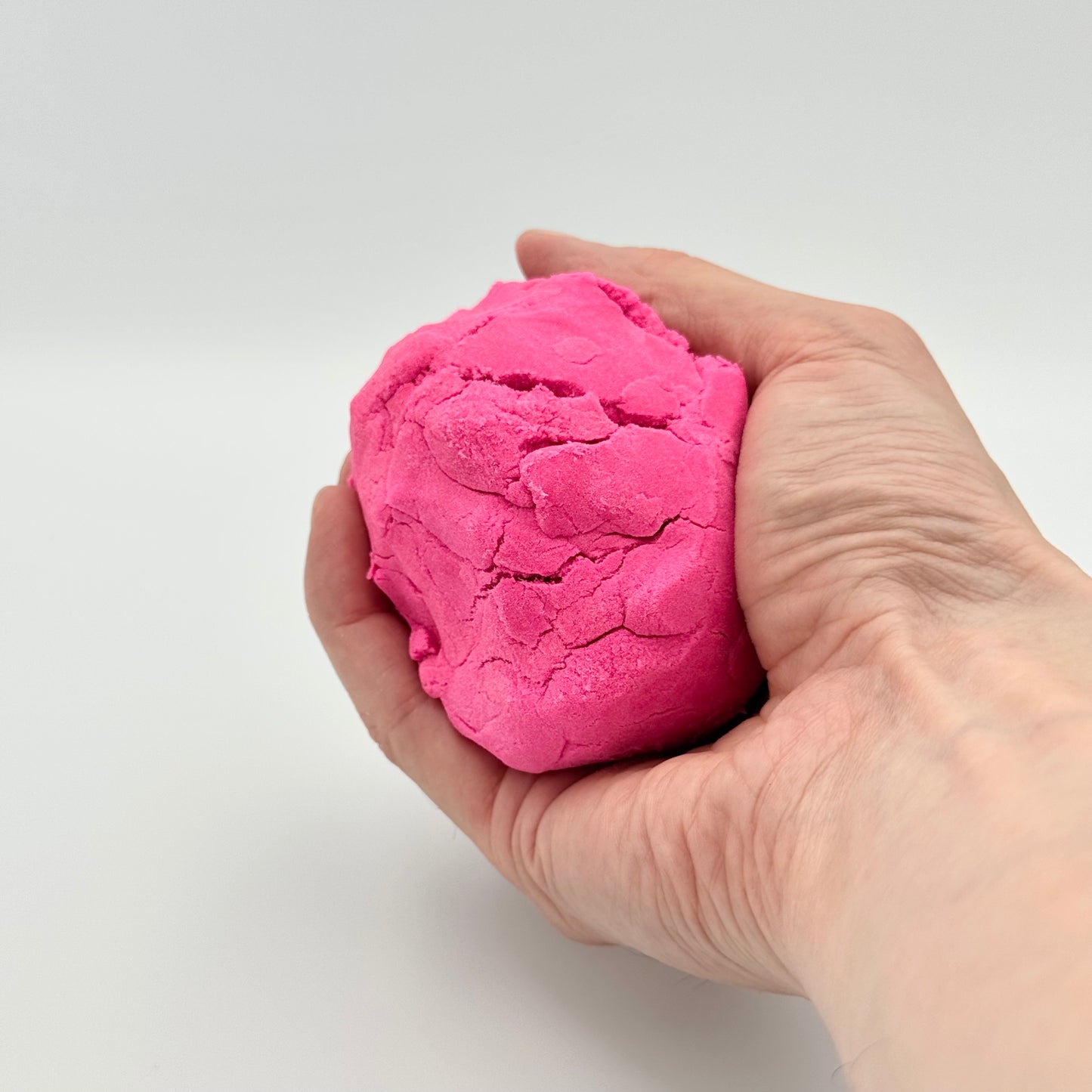 Kugel aus rosa Magic Clay Knet-Sand in der Hand – Kinetischer Sand zum Kneten & Entspannen
