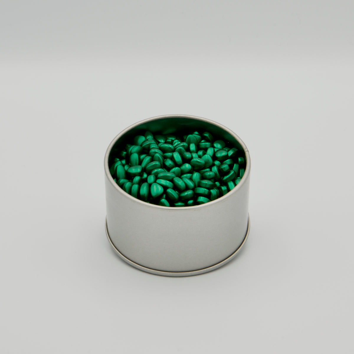 Offene, runde Metalldose, gefüllt mit grünen, magnetischen Knet-Pellets