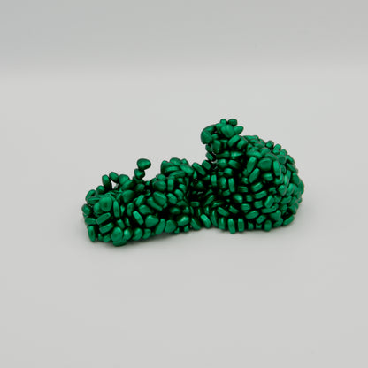Freigeformte Struktur aus vielen kleinen, grünen, magnetischen Knet-Pellets auf weißem Hintergrund