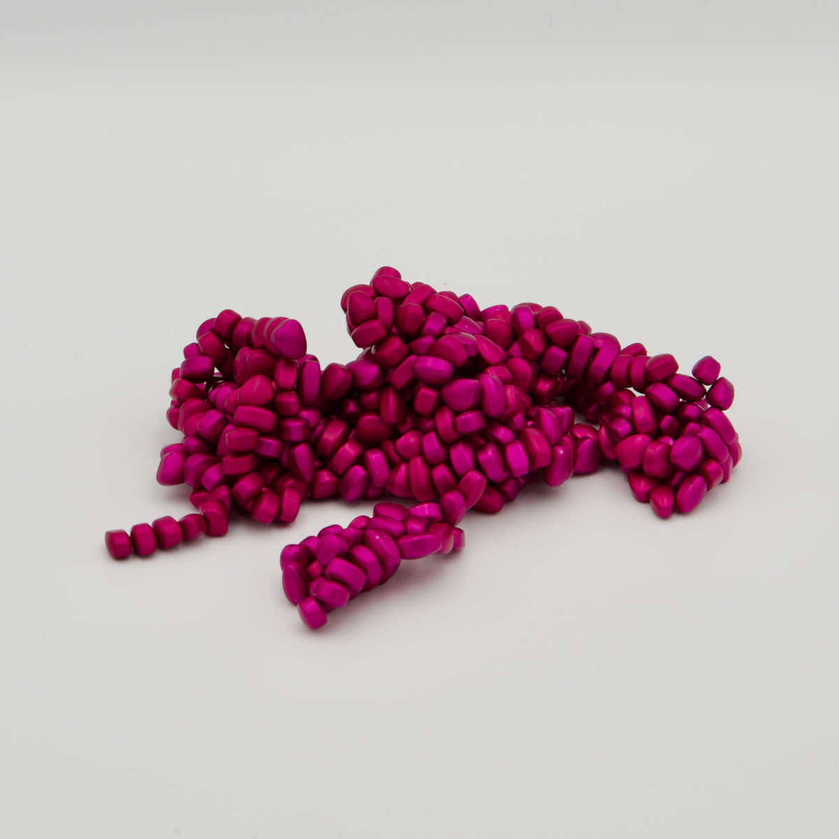 Geformte Masse aus unzähligen kleinen, pinken, magnetischen Pellets auf weißem Hintergrund