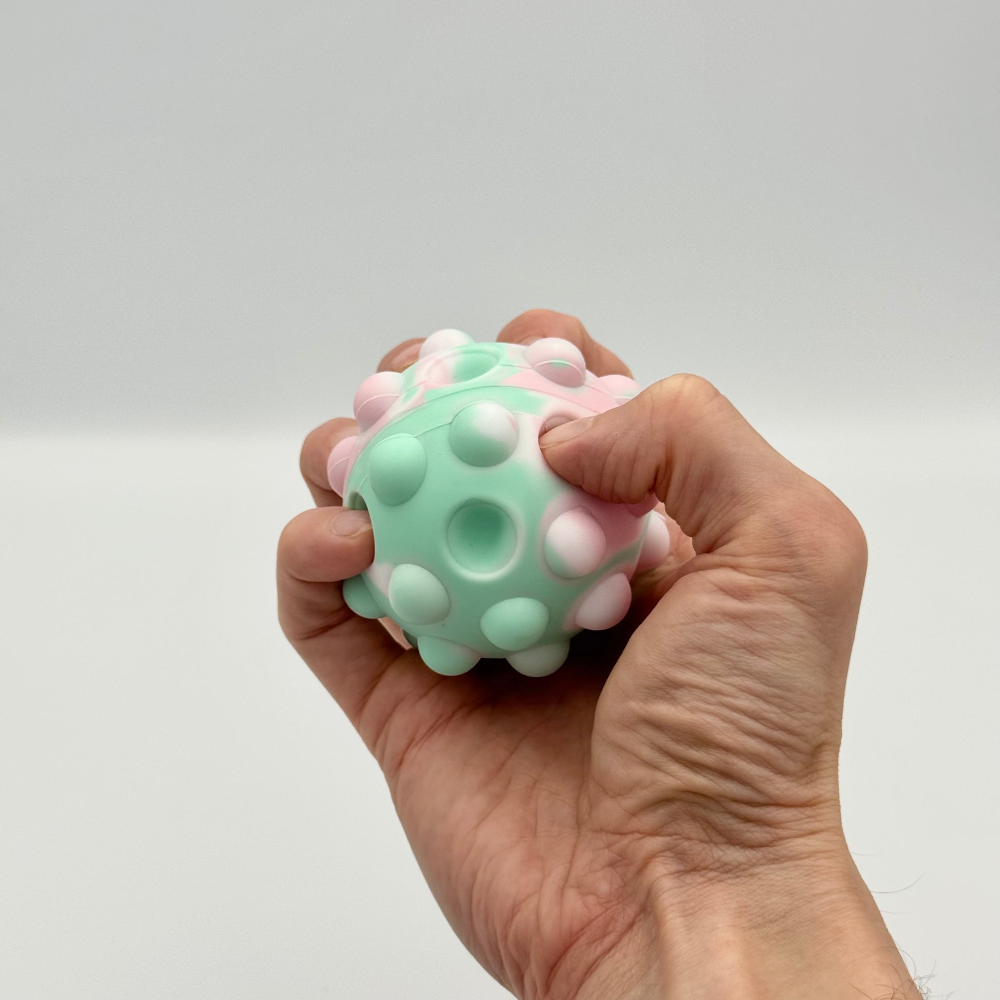 Pastellfarbener 3D Pop Ball aus Silikon in der Hand – Pop It Squeeze Ball gegen Stress