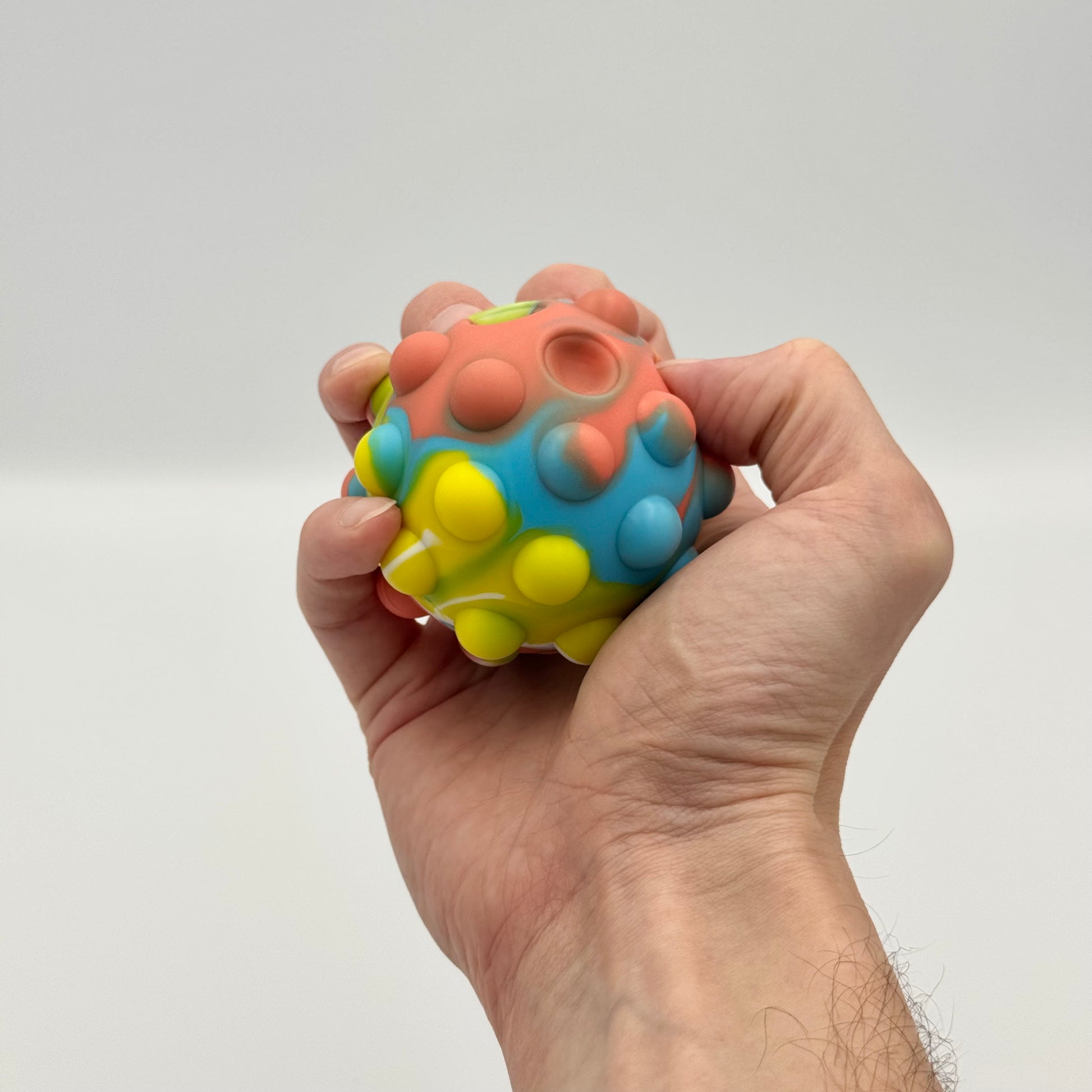 Regenbogen Pop It Ball wird in der Hand gedrückt – Squeeze Pop Ball Fidget Toy