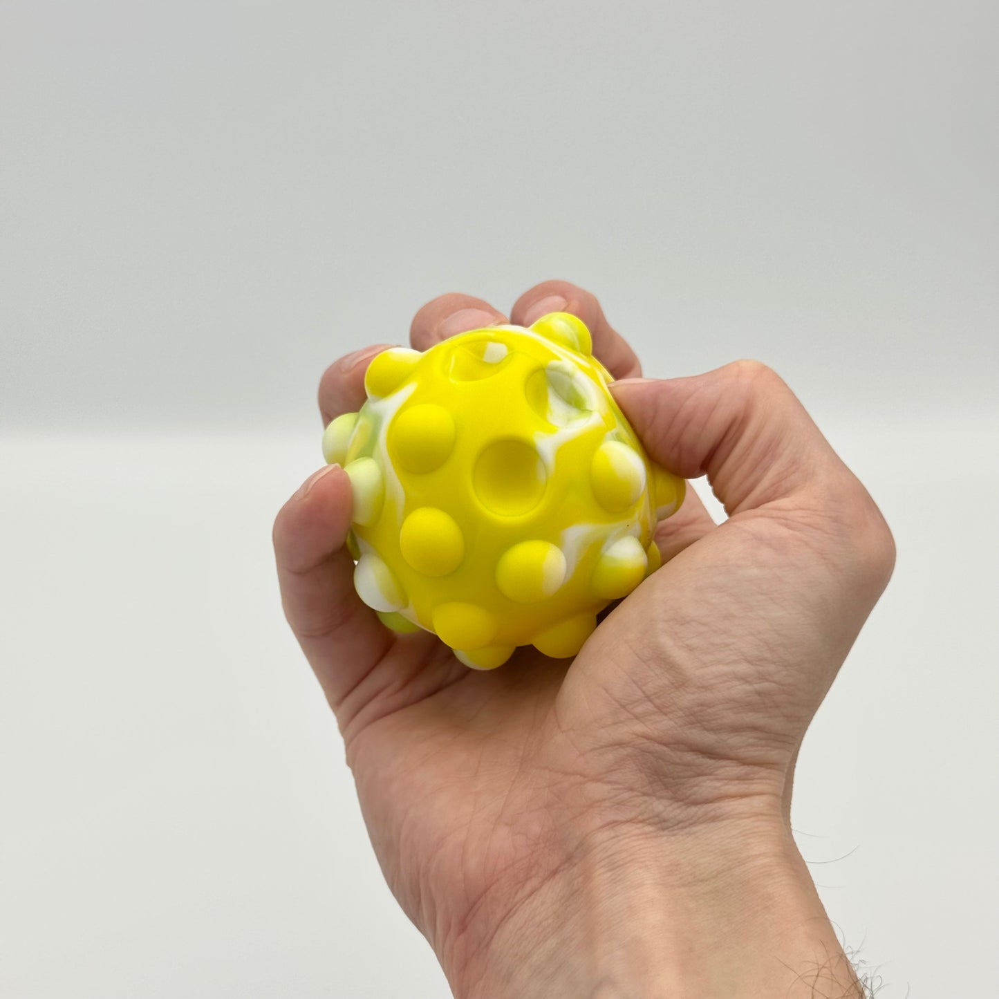 Gelb-grüner 3D Pop It Ball wird in der Hand gedrückt – Squeeze Pop Ball Fidget Toy