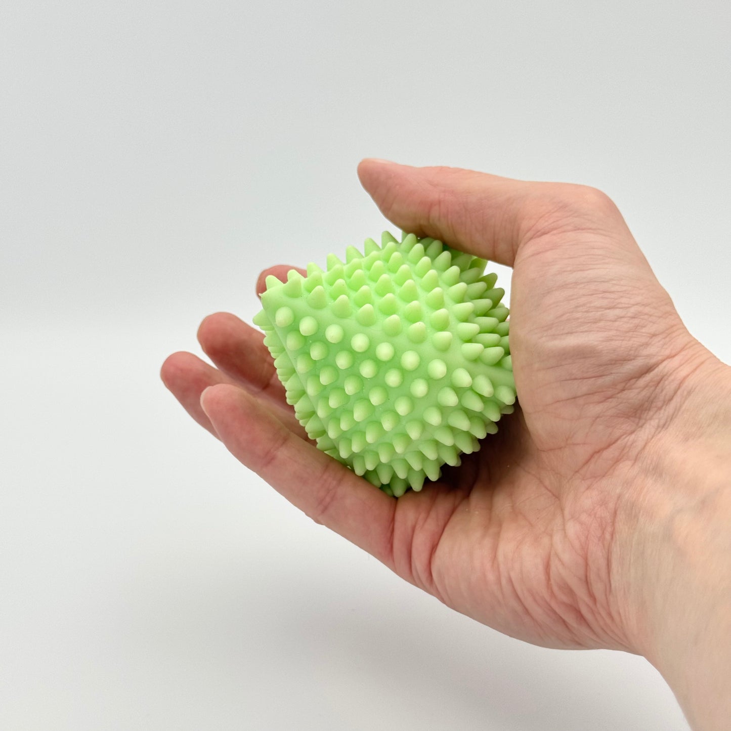 Hellgrüner Pyramiden-Anti-Stressball mit Noppen in der Hand – Taktiles Squeezy Fidget Toy