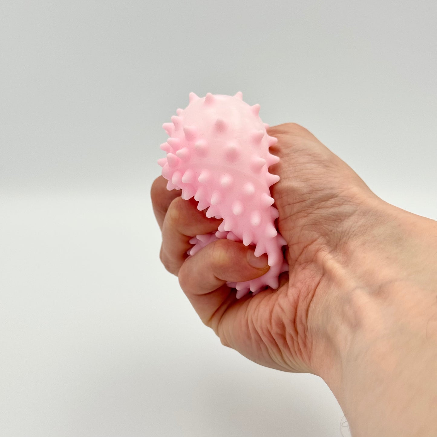 Rosa Pyramiden-Anti-Stressball mit Noppen wird in der Hand gedrückt – Taktiles Fidget Toy