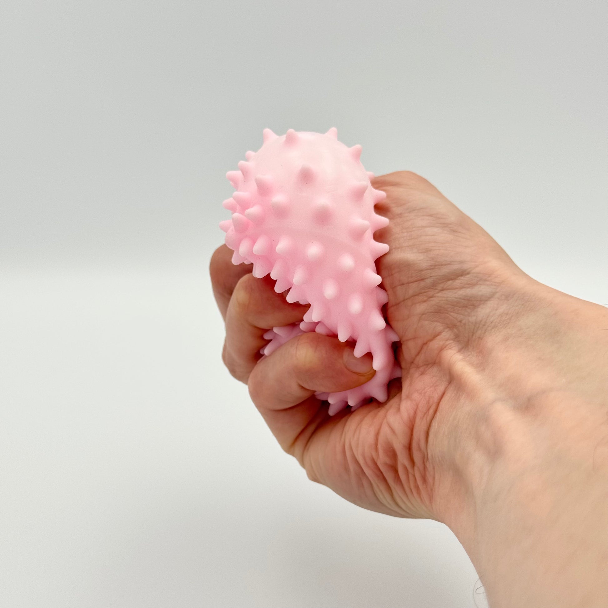 Rosa Pyramiden-Anti-Stressball mit Noppen wird in der Hand gedrückt – Taktiles Fidget Toy