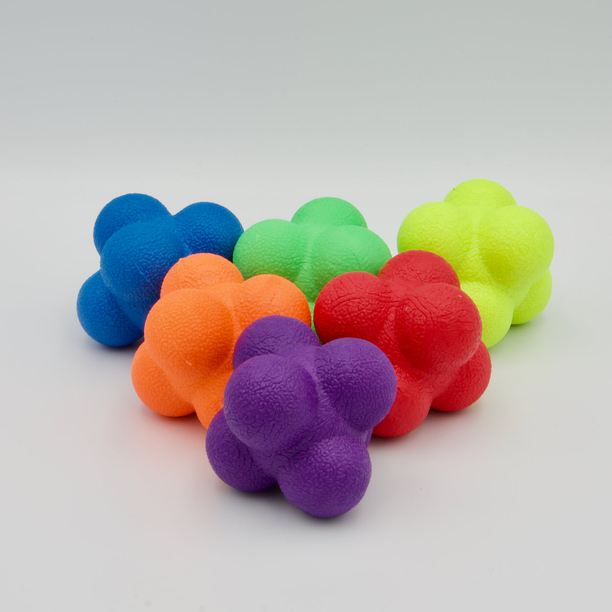 Sechs bunte, strukturierte Reaktionsbälle in verschiedenen Farben, in Formation angeordnet.