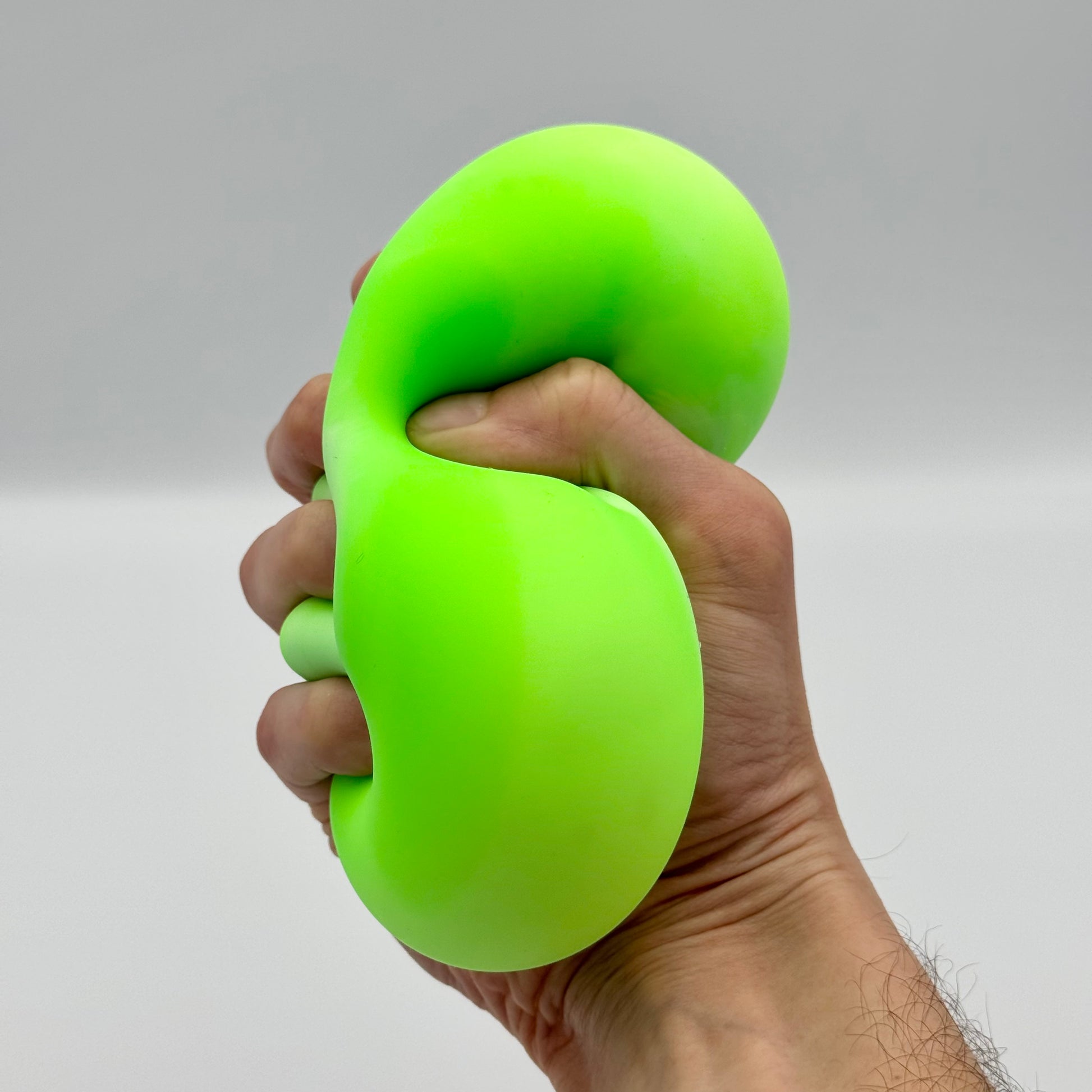 Neongrüner Squeeze Ball wird fest in der Hand gedrückt – Elastischer Anti-Stressball