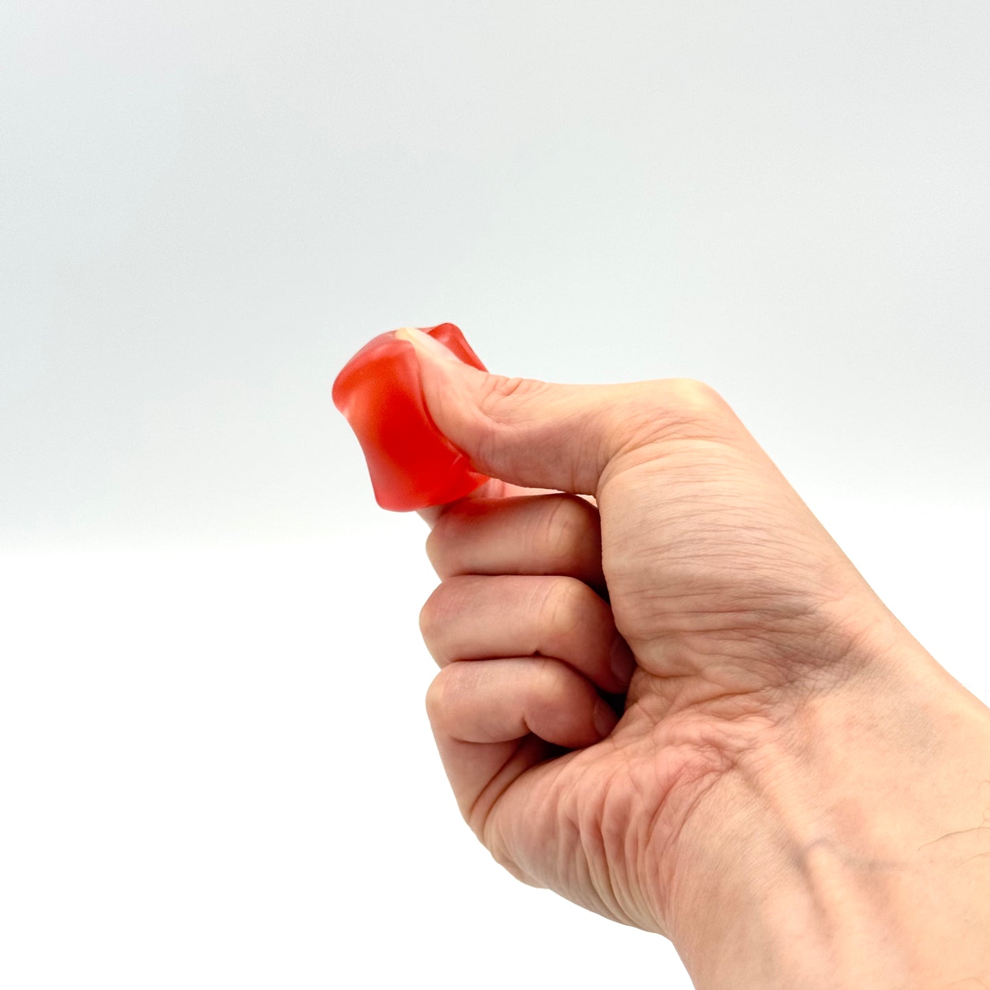 Roter Squish Cube Fidget Würfel aus Gelee-Material wird gedrückt 
