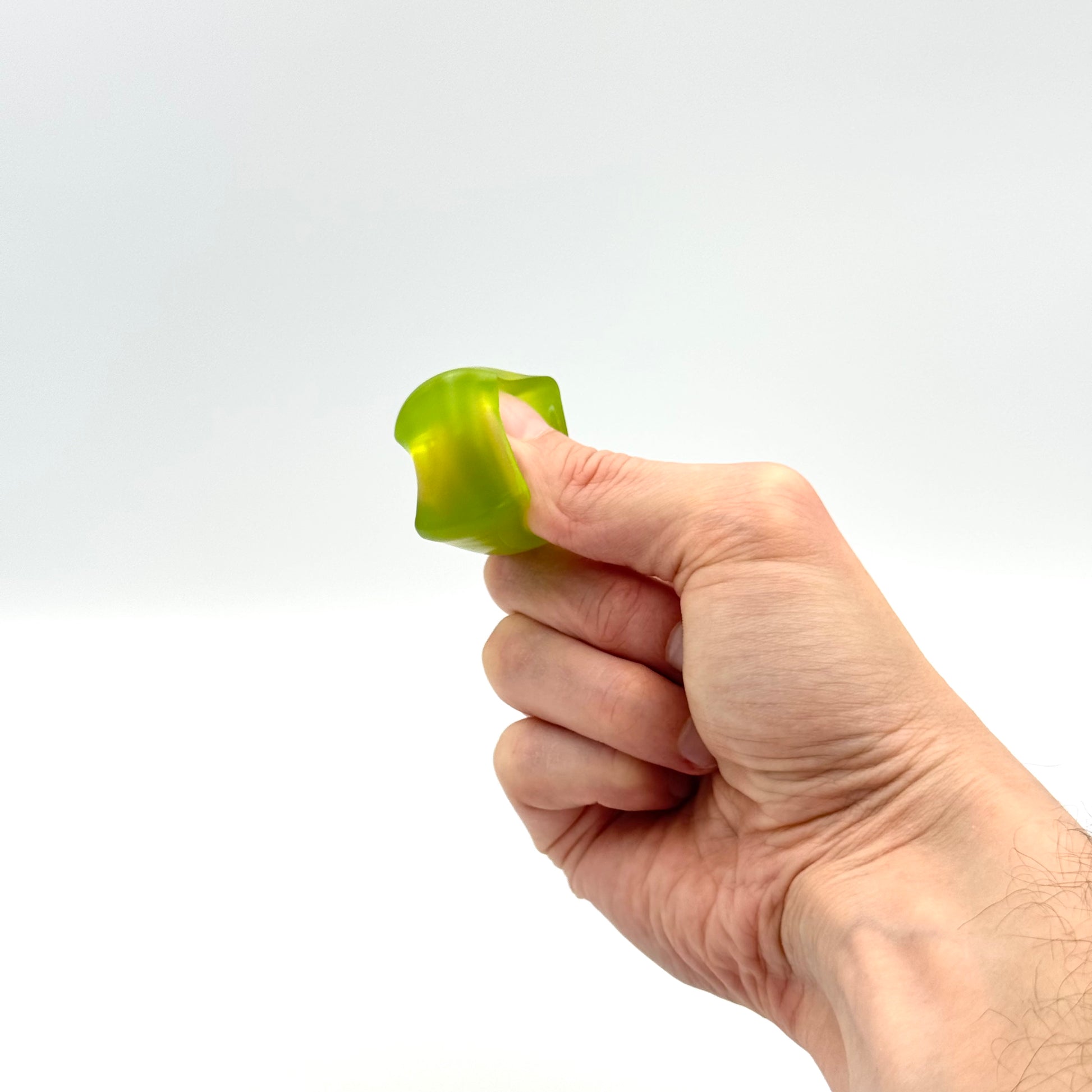Grüner Mini Squish Cube Fidget Würfel wird mit Fingern gedrückt 