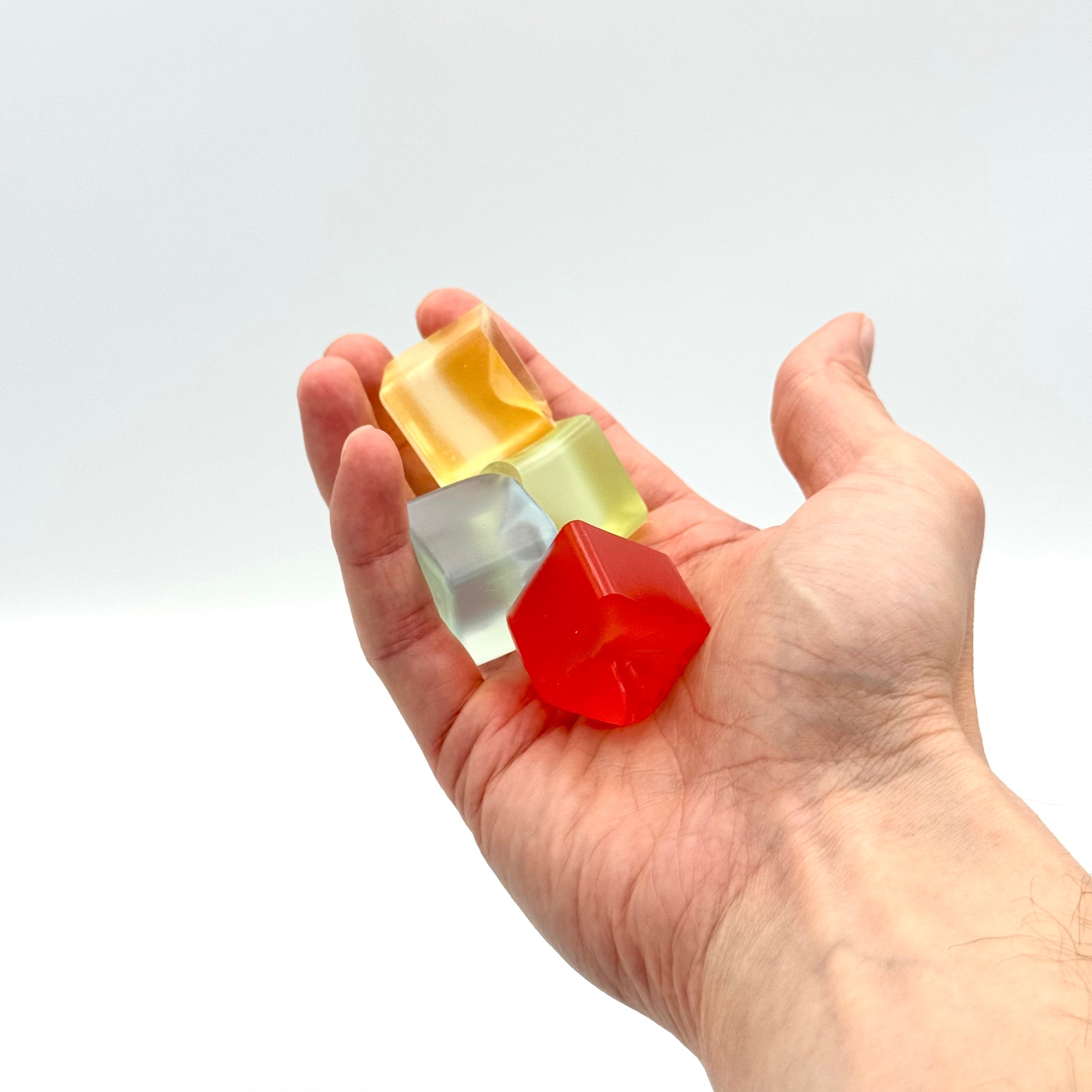 Vier transparente Mini Squish Cubes in einer Hand – Fidget Würfel