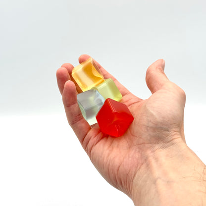 Vier transparente Mini Squish Cubes in einer Hand – Fidget Würfel