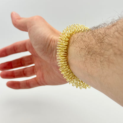 Goldener Therastar Handmassagering wird am Handgelenk gerollt – Akupressur Armband