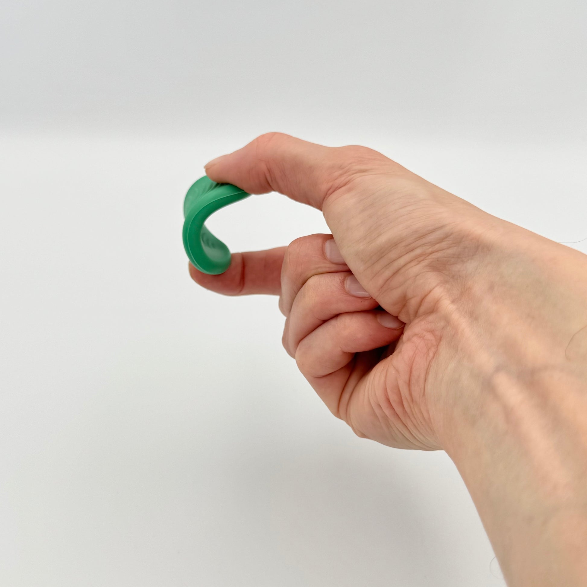 Flexibler grüner Worry Stone aus Silikon wird mit Fingern gebogen – Sensorisches Fidget Toy